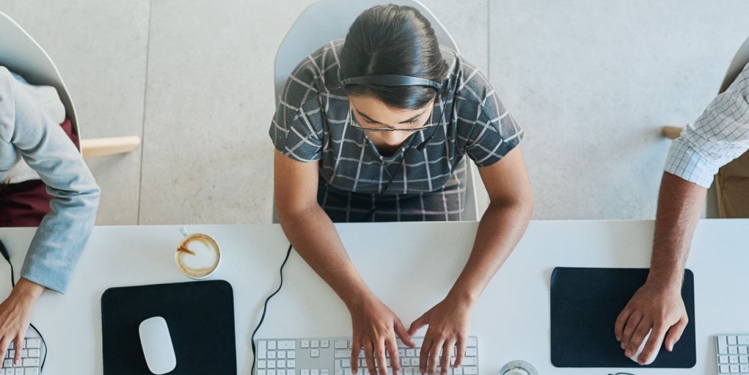 Overhead video of service representatives with headsets on working on computers, reminiscent of a call center.