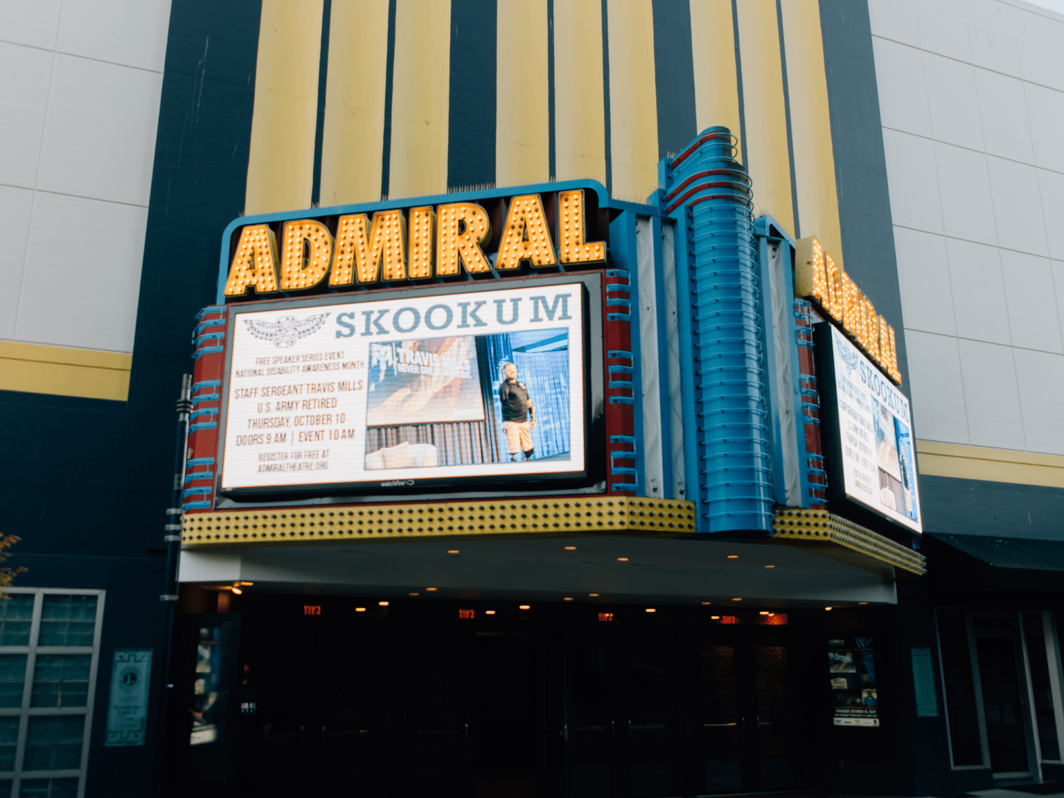 A marquee outside of the Admiral Theater with signage promoting speaker Travis Mills.