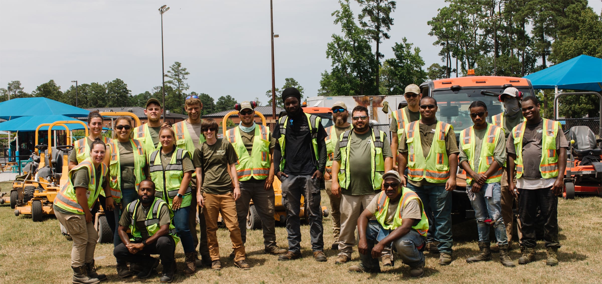 Large group of employees in high visibility vests volunteering for work day at local park.