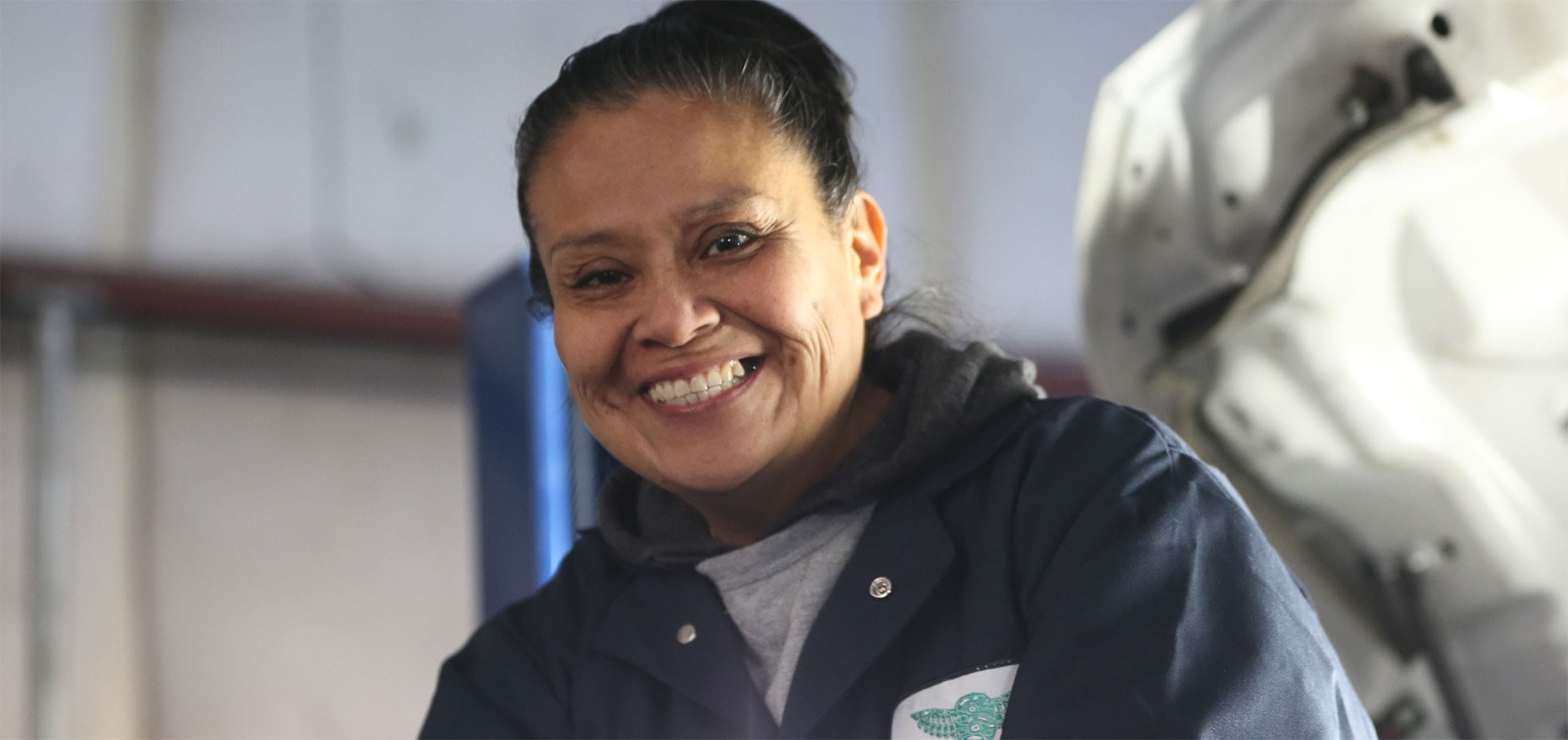 Smiling female employee in vehicle maintenance bay.