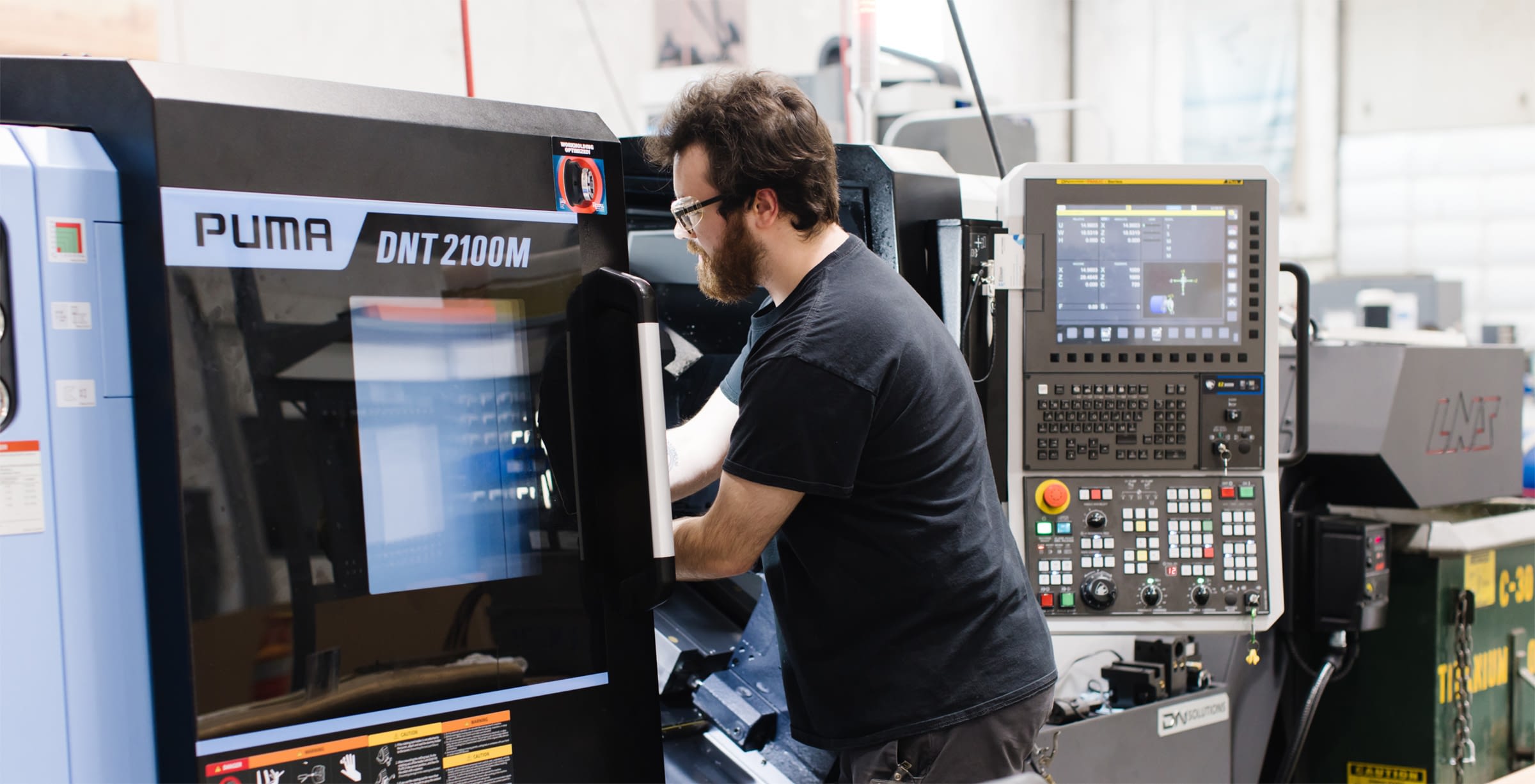 Employee working on industrial PUMA DNT 2100M equipment.