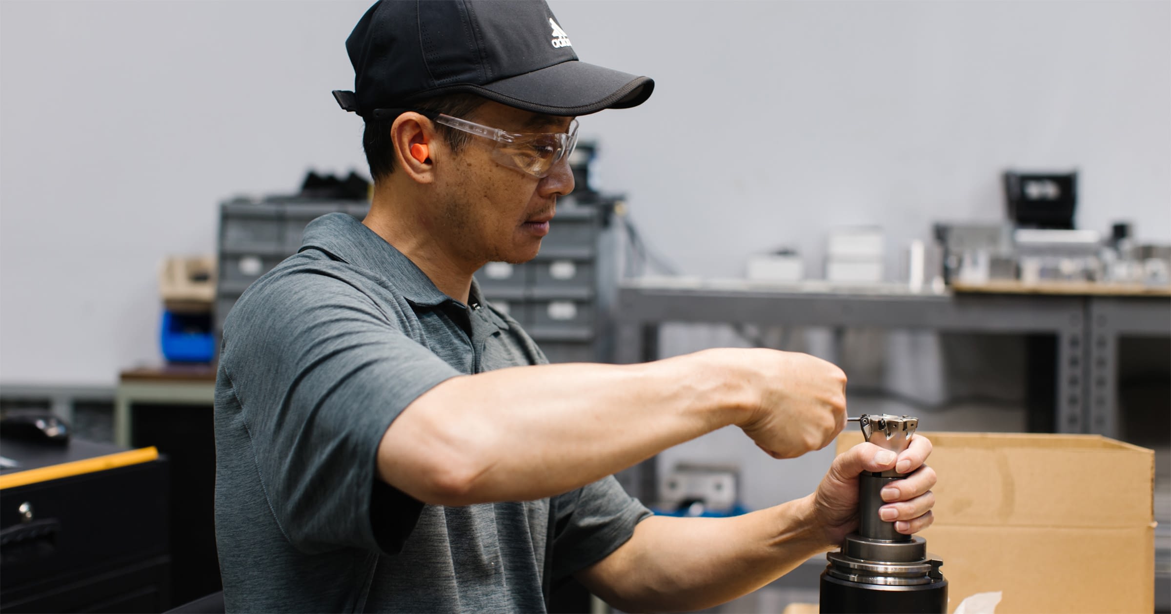 Employee in safety glasses and hat working on equipment.