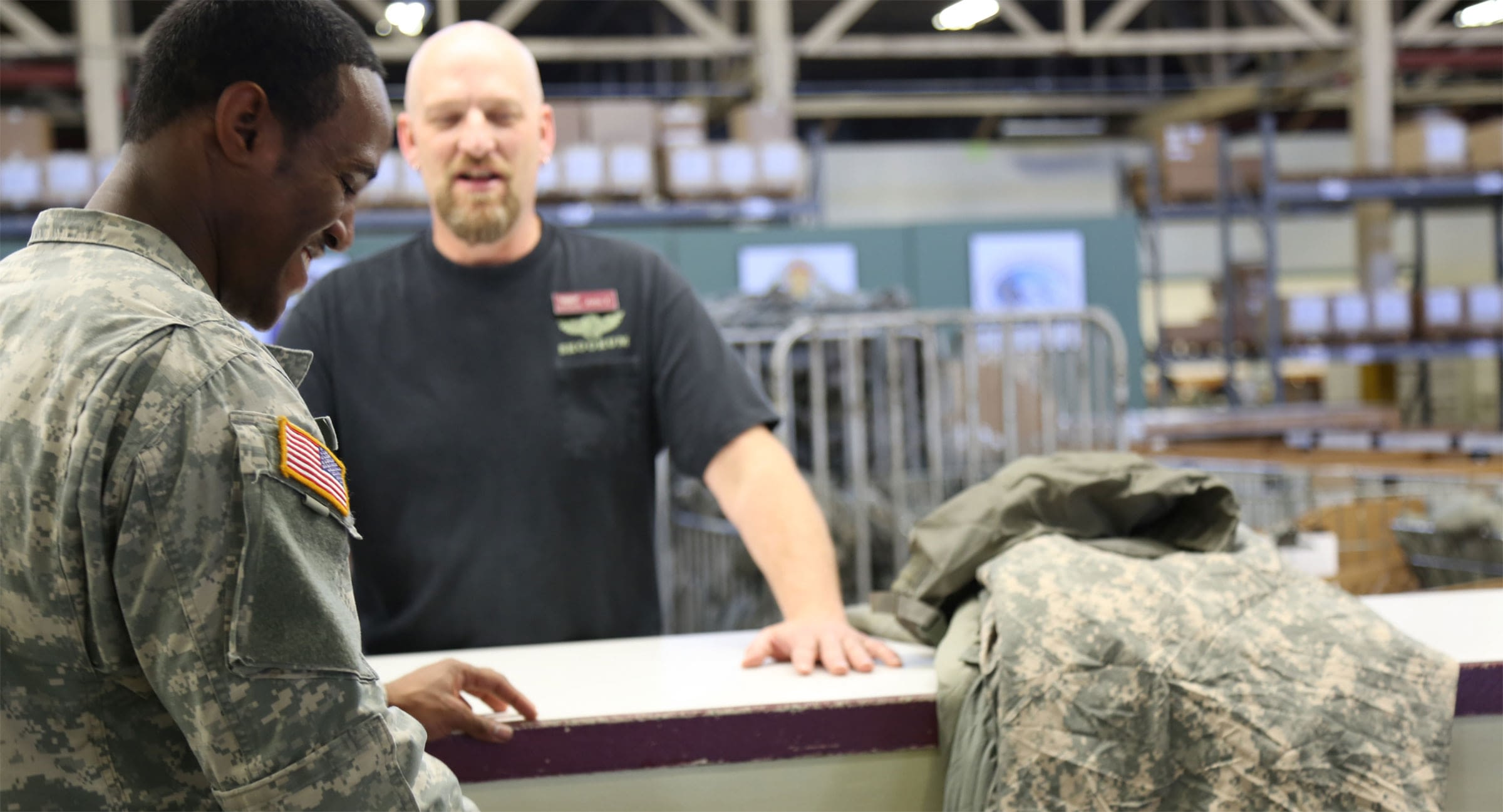 Soldiers and Tessera employee consulting in large warehouse facility.