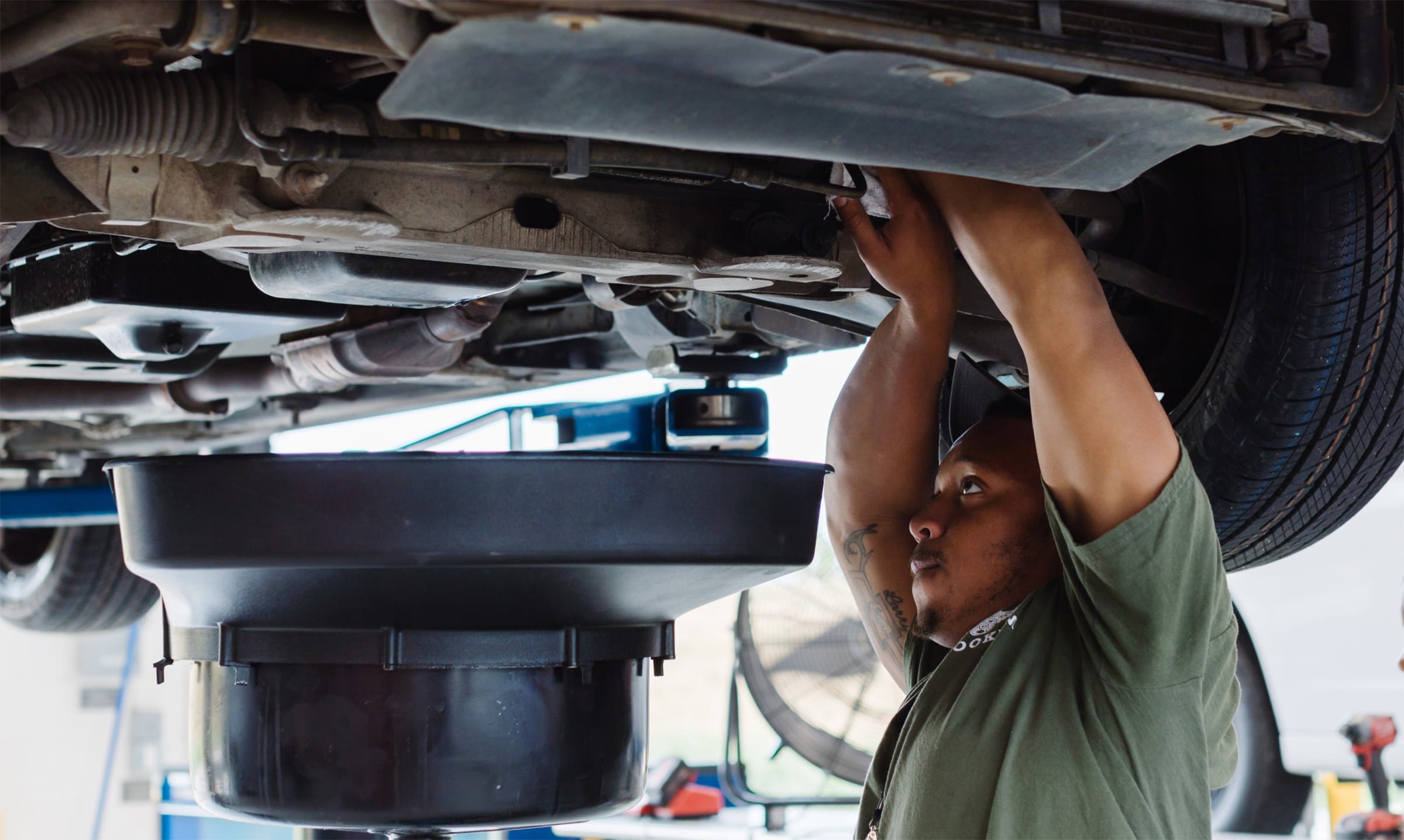 Employee servicing the underside of a vehicle on a lift.
