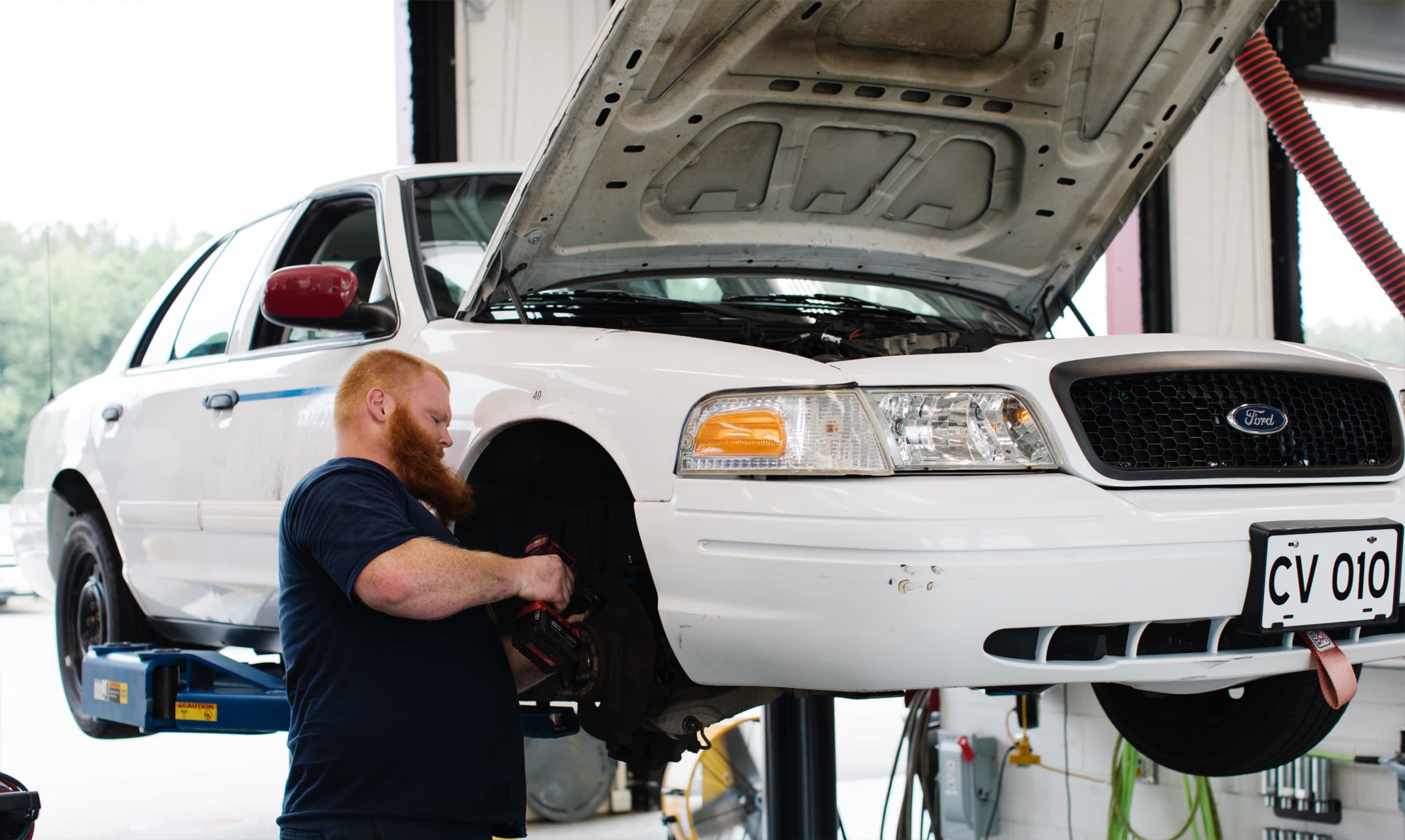 Employee working on the tire of a white car on a lift.
