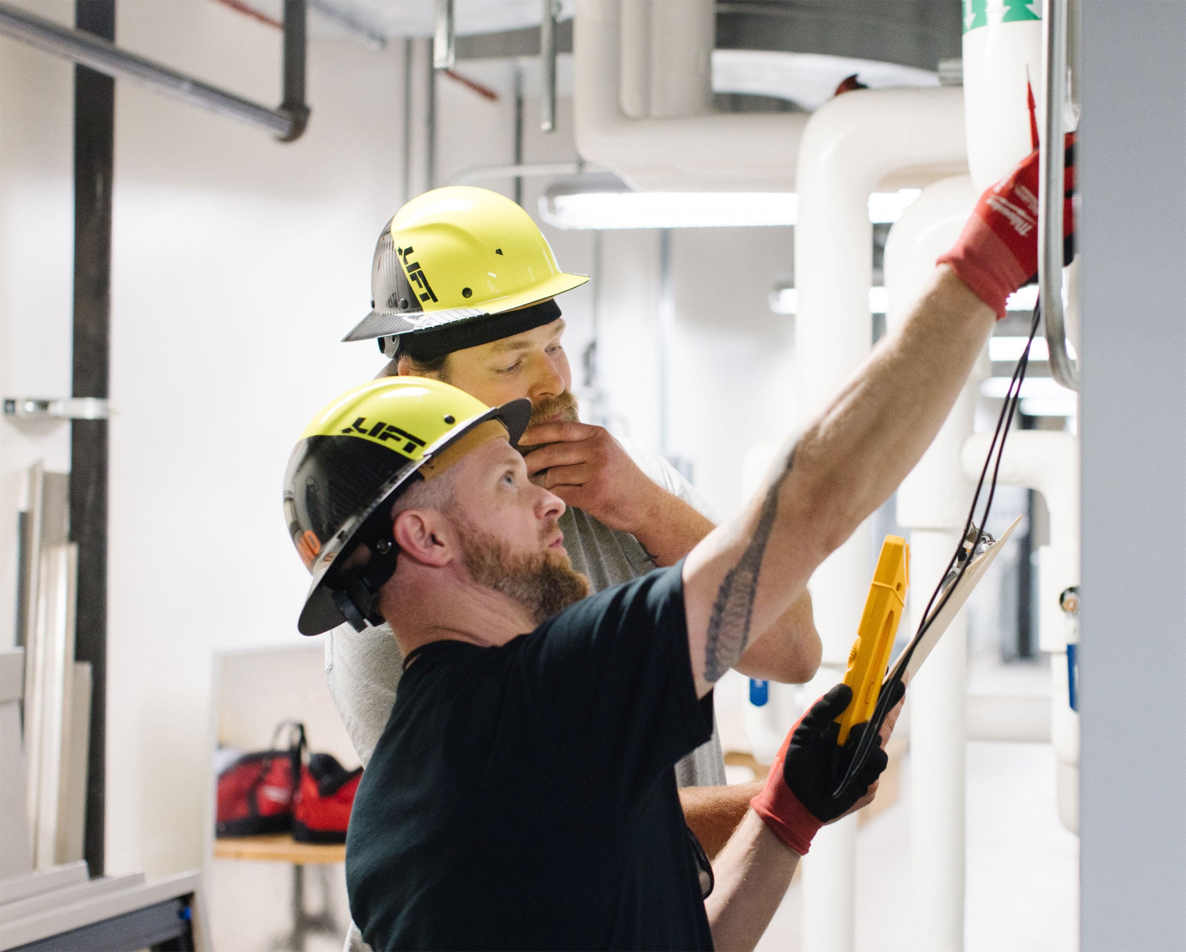 Two men in yellow hard hats inspecting facility equipment.