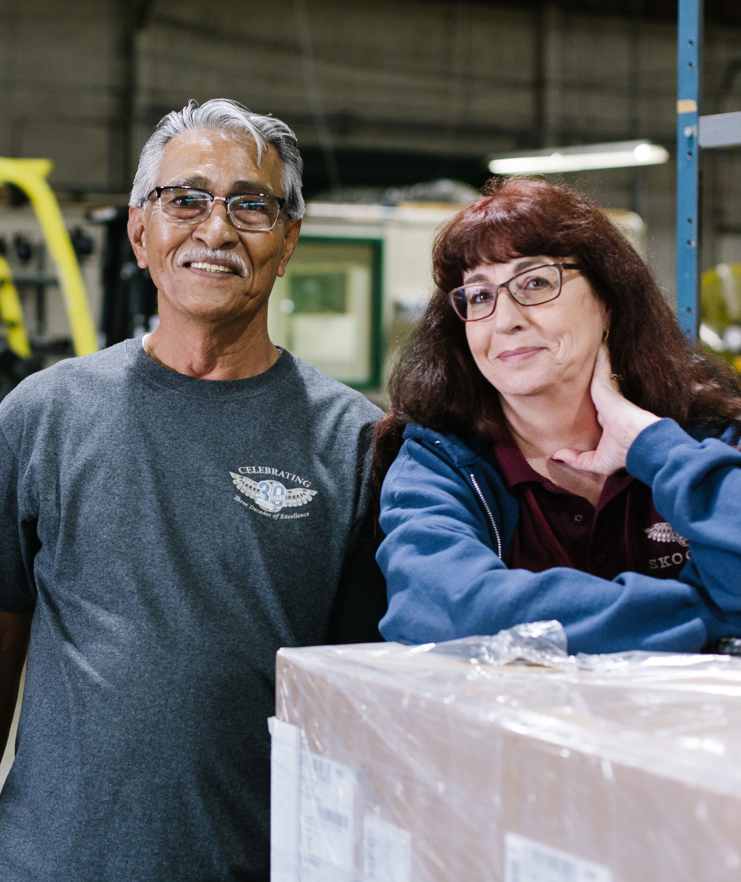 Two employees pause for a photo while working in a warehouse.