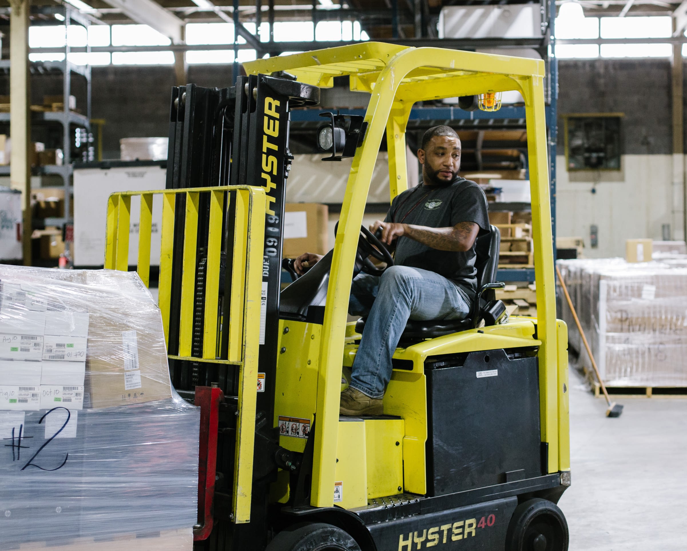 Employee operating a yellow forklift in a warehouse.