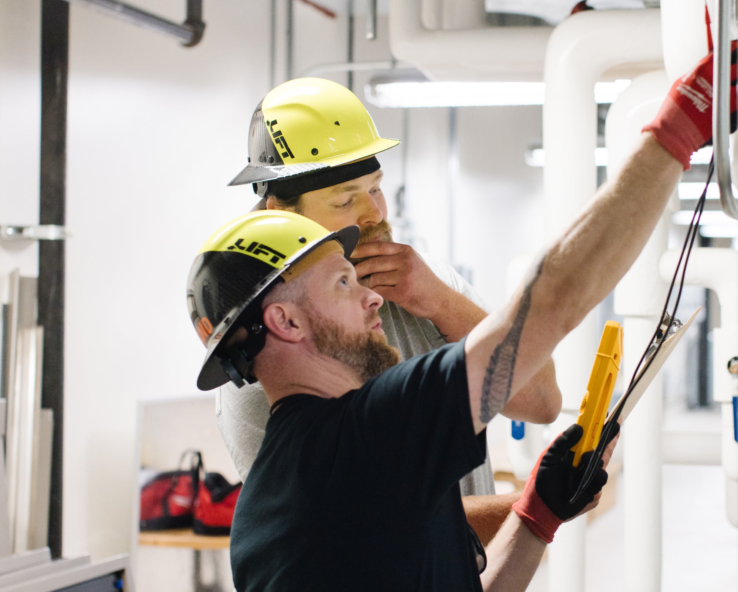 Two employees in hard hats running a diagnostic check on a facility.