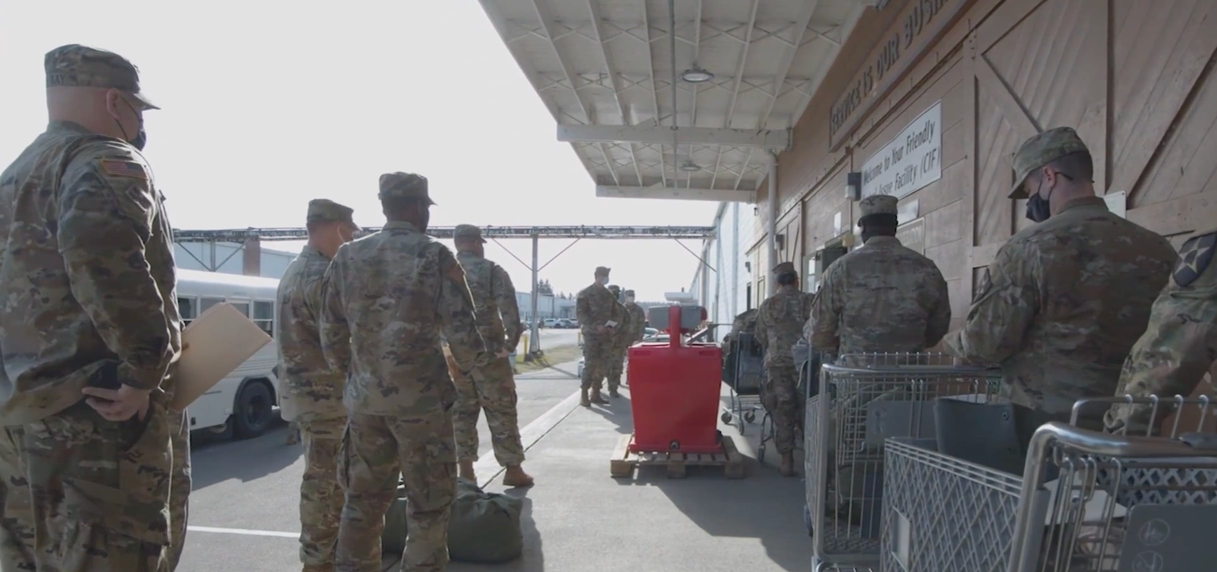 A group of U.S. Army soldiers in uniform wait in line outside a Central Issue Facility (CIF), returning or receiving equipment as part of the military supply process.