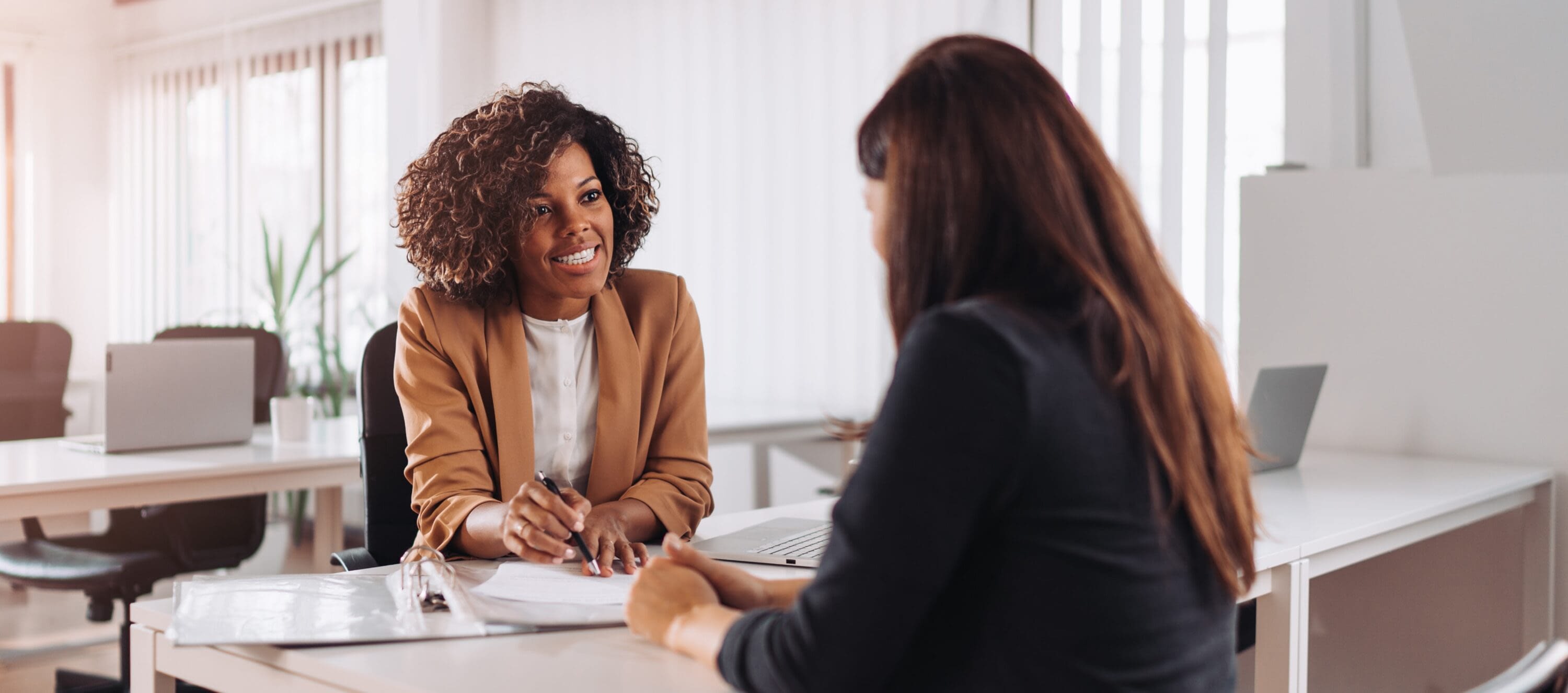 An employer reviews a candidate’s resume at a desk, demonstrating Tessera’s role in fostering fair hiring practices and creating pathways to employment.